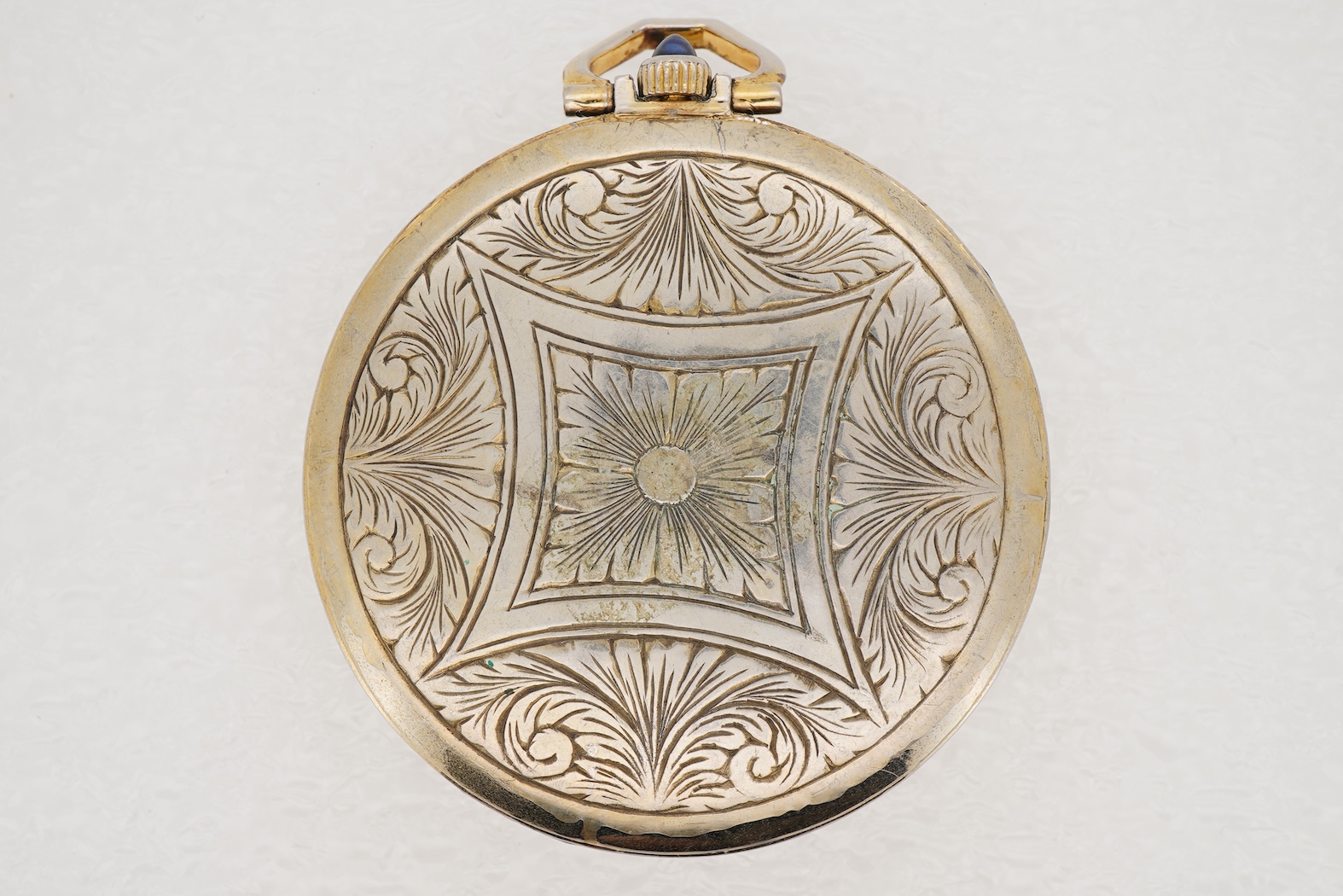 A French Art Deco parcel gilt white metal open faced dress pocket watch, with synthetic sapphire set border and winding crown